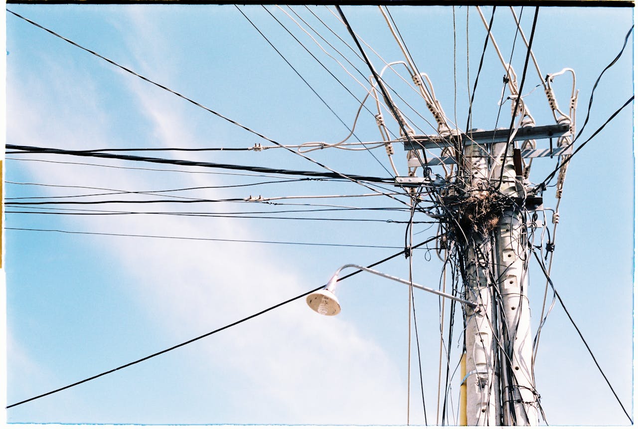 why-choose-us An intricate network of power lines and a lamp post against a clear blue sky.