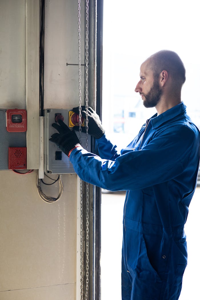 services-02 A technician in blue overalls operates a control switch inside a facility, focused and attentive.